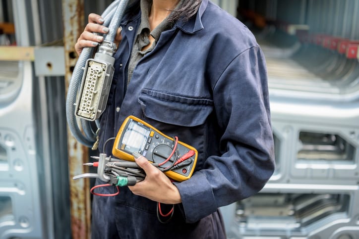 Palmetto Electrical Contractors | worker holding equipment in a car factory
