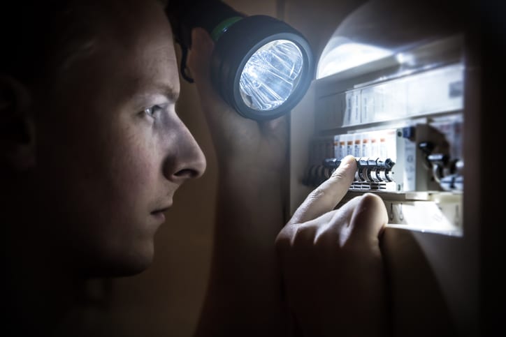 Palmetto Electrical Contractors | man with flashlight restoring power on a circuit breaker